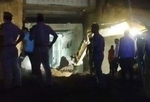 Group of workers in a rubble-filled, dim site standing with hands on hips, inspecting a collapsed underground area.