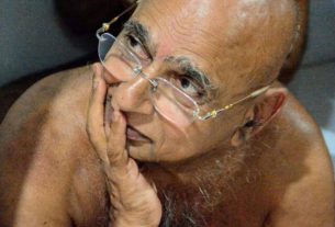 Older man with glasses resting his face on his hand, looking thoughtful/captive in a candid moment.