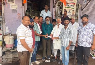 Group of men standing outside a shop, exchanging a document as others look on.