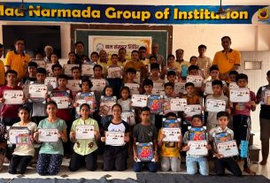 Group of students and teachers posing with certificates after a ceremony in a classroom; a banner for the institution is overhead.